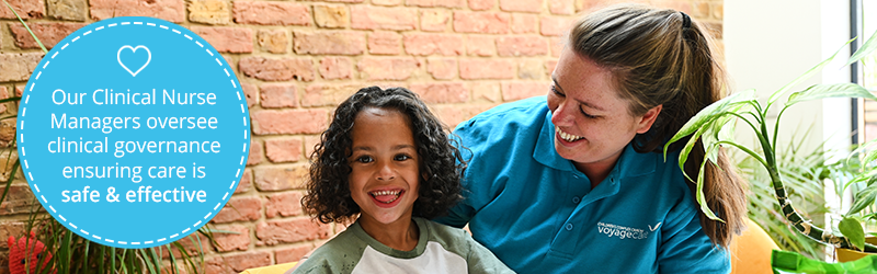 Young boy with complex needs smiles at the camera. Supported by a healthcare assistant next to him on the right smiling down at him. On the left is a blue roundal with white dashes around the inside. There's white text that reads, "Our clinical nurse managers oversee clinical governance ensuring care is safe and effective." alongside a white heart icon. 